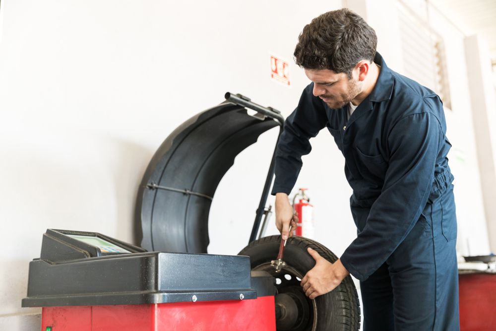 A mechanic installing tire weights on a tire.