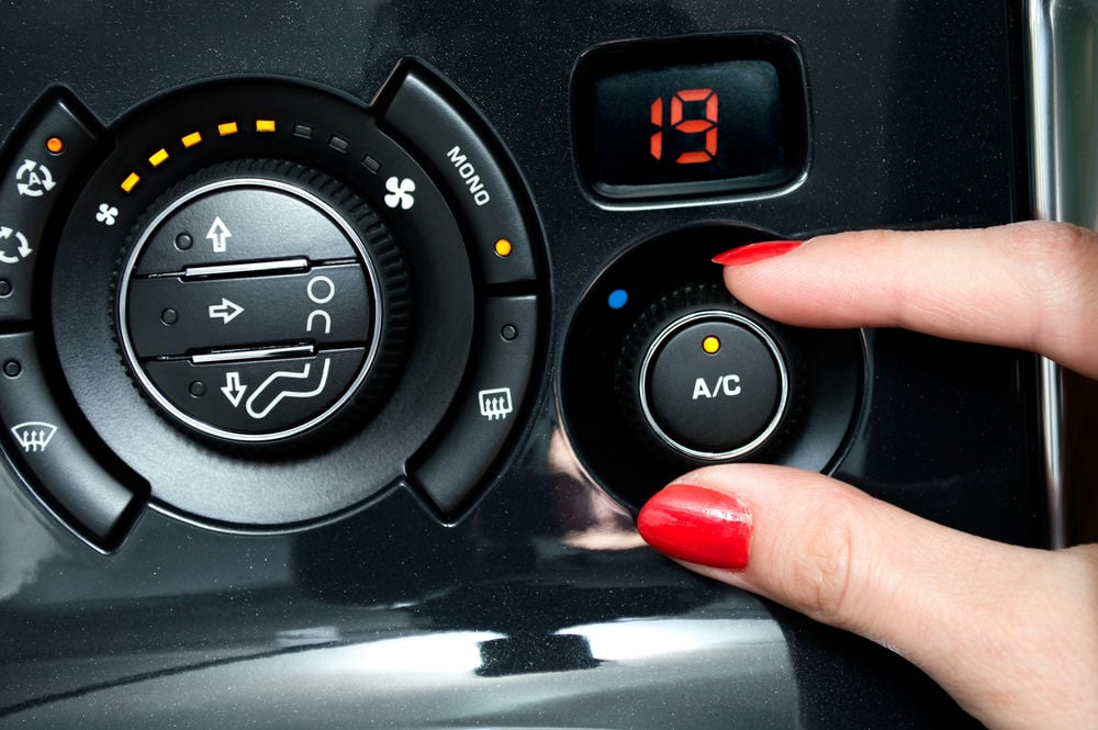 A woman turning the AC on in a vehicle.