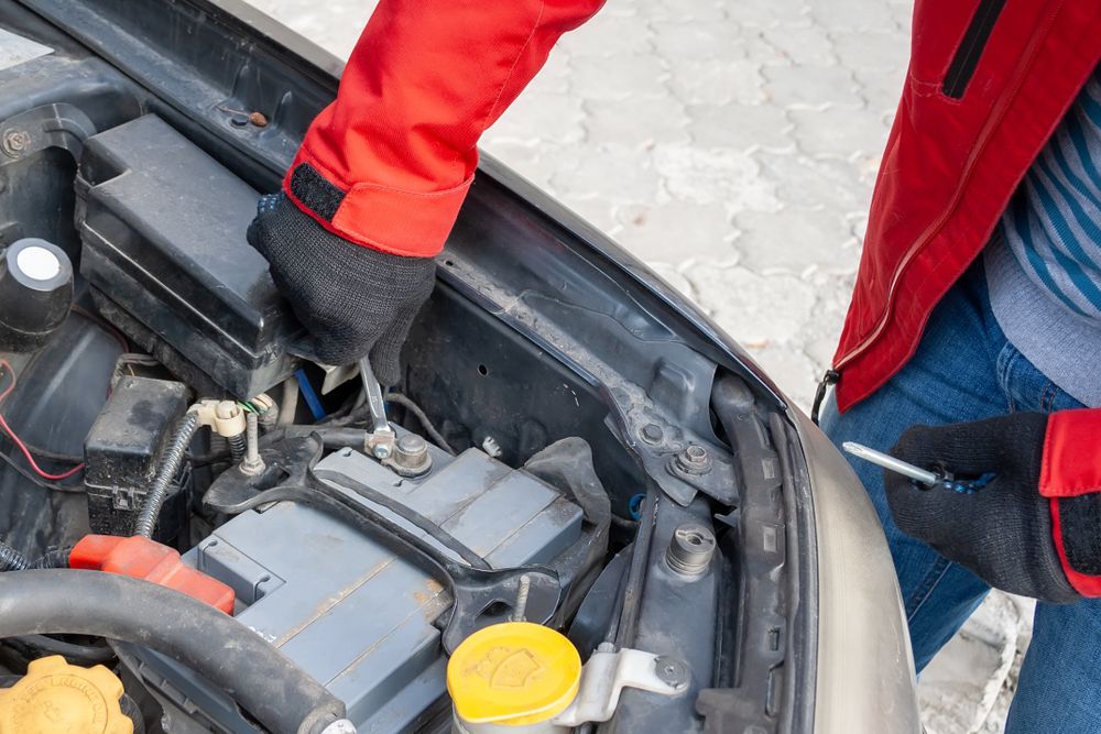 Disconnecting the negative battery cable from a car battery.