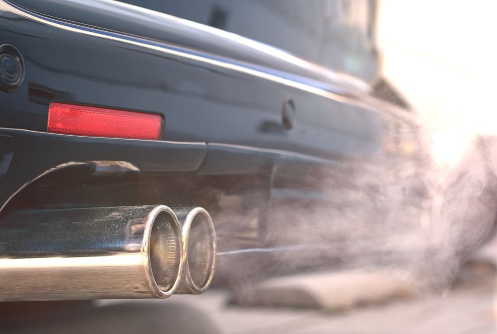 Exhaust exiting out of the muffler at the rear of a car.