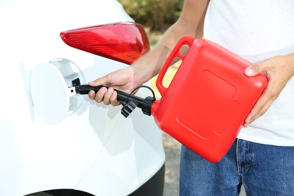 Filling a car with gasoline from a portable container.