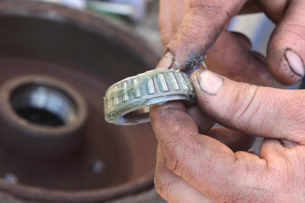 A mechanic greasing a new wheel bearing.