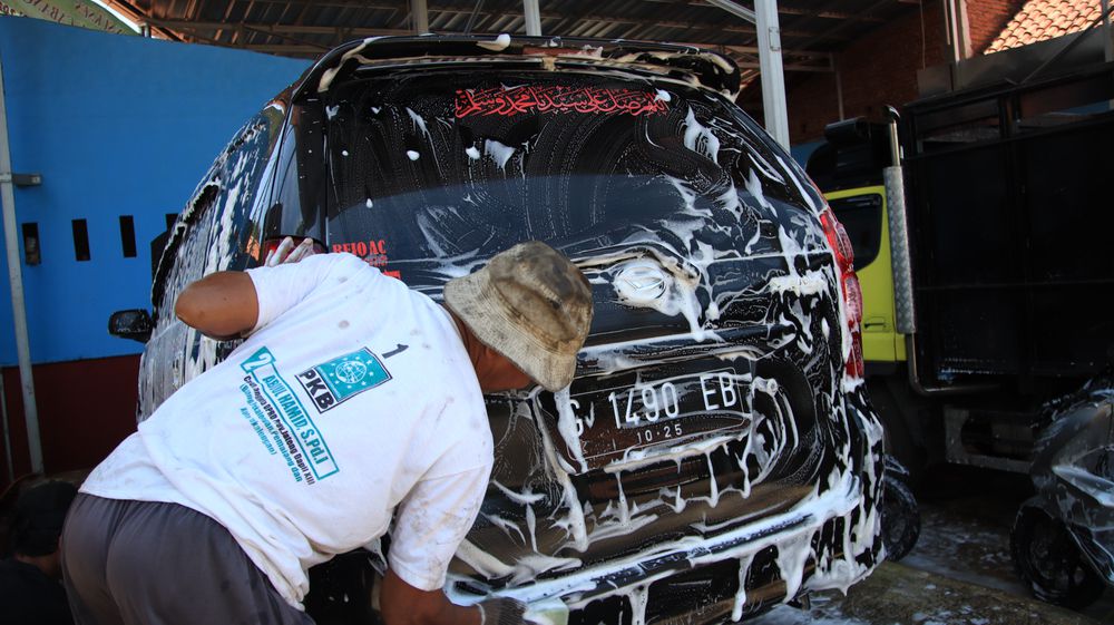 Hand washing a car with soapy water.