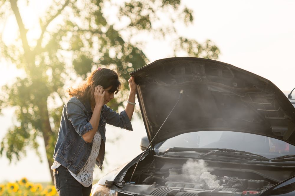 Lady looking down at overheating engine