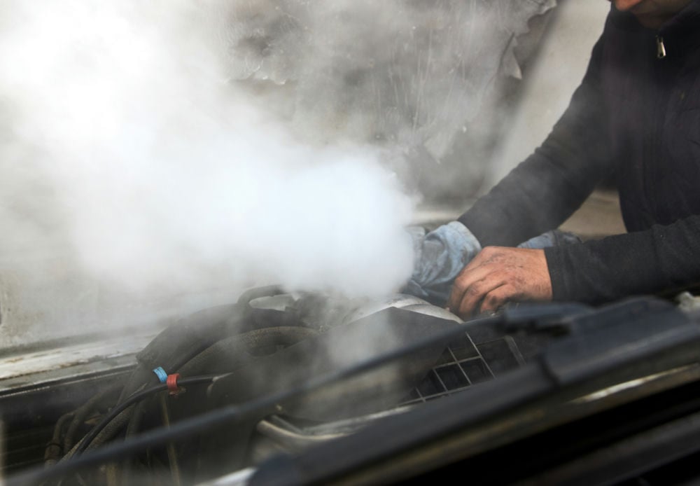 A man investigating an overheating engine.