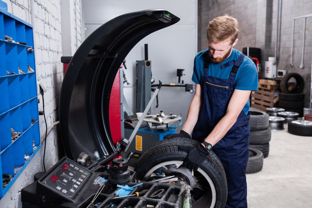 Mechanic balancing a tire on a tire balancing machine