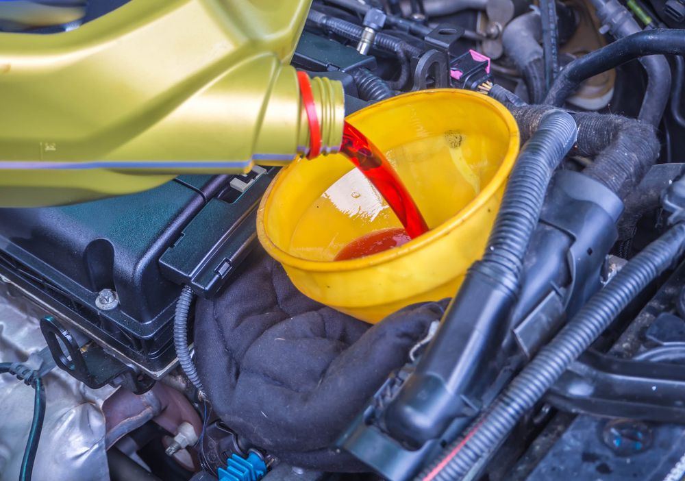 Mechanic filling a transmission with transmission fluid.