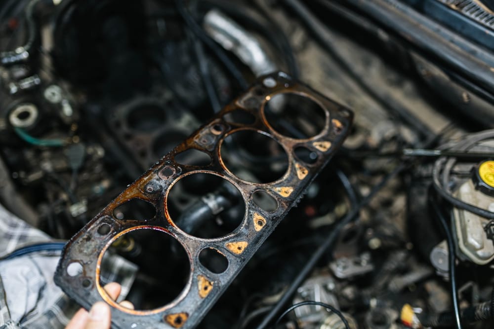 A mechanic holding a damaged head gasket.