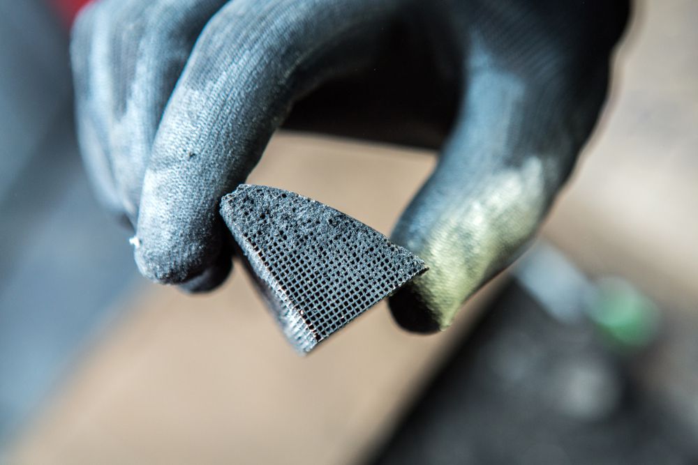 Mechanic Holding Piece Of Clogged Catalytic Converter