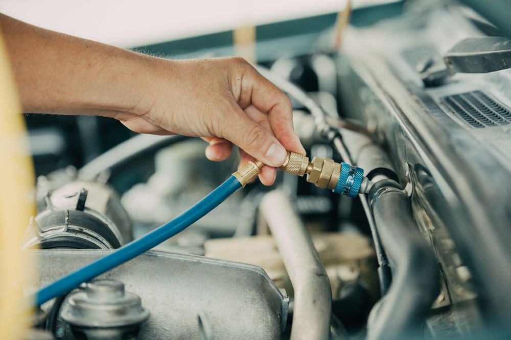 A mechanic hooking up his AC servicing machine to a customer.