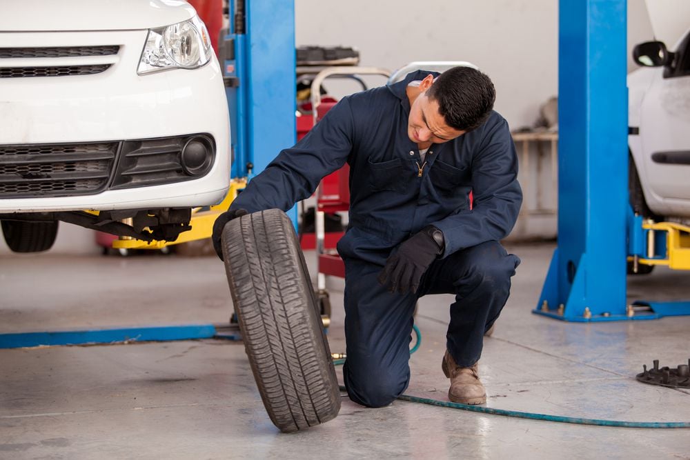 Mechanic inspecting a tire during tire rotation.