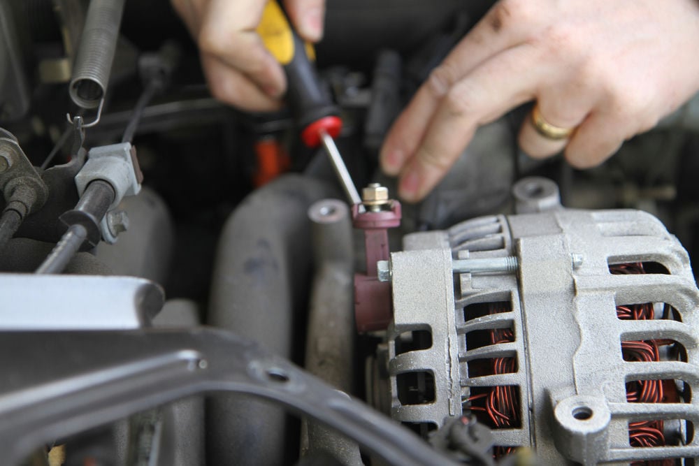 A mechanic installing a new alternator.