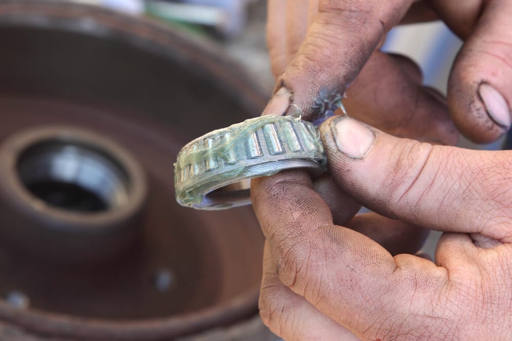 A mechanic packing a wheel bearing with grease.