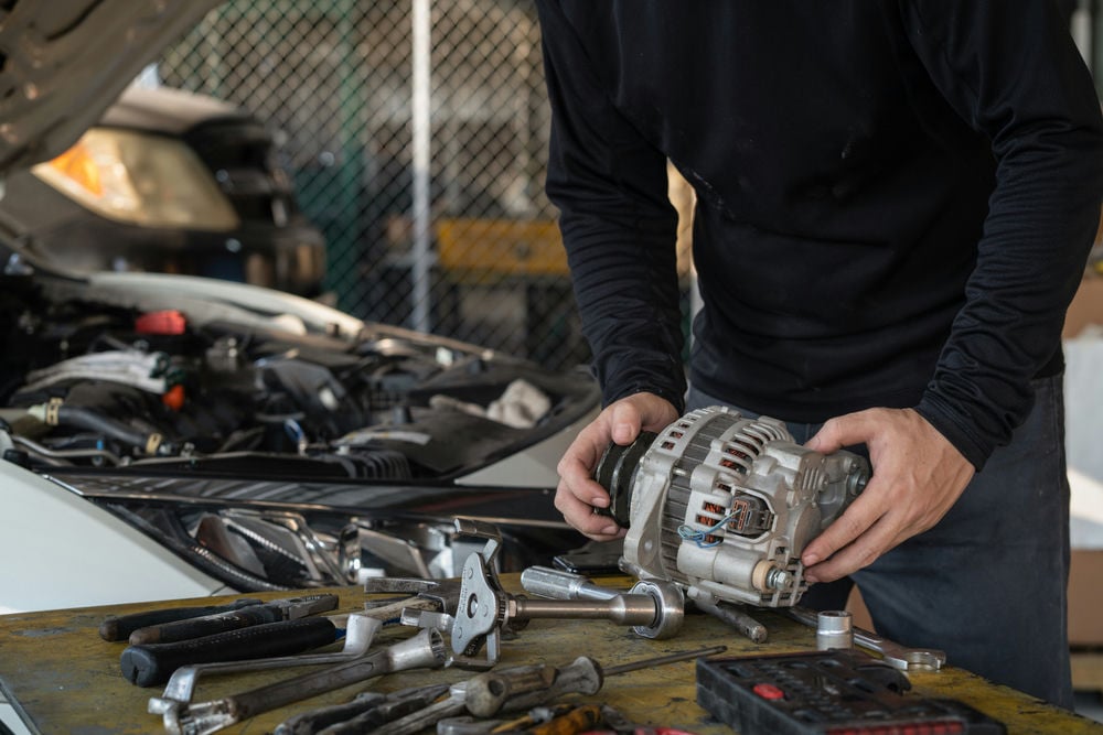 A mechanic preparing to install a new alternator.