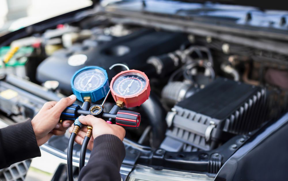 A mechanic recharging a car AC system.