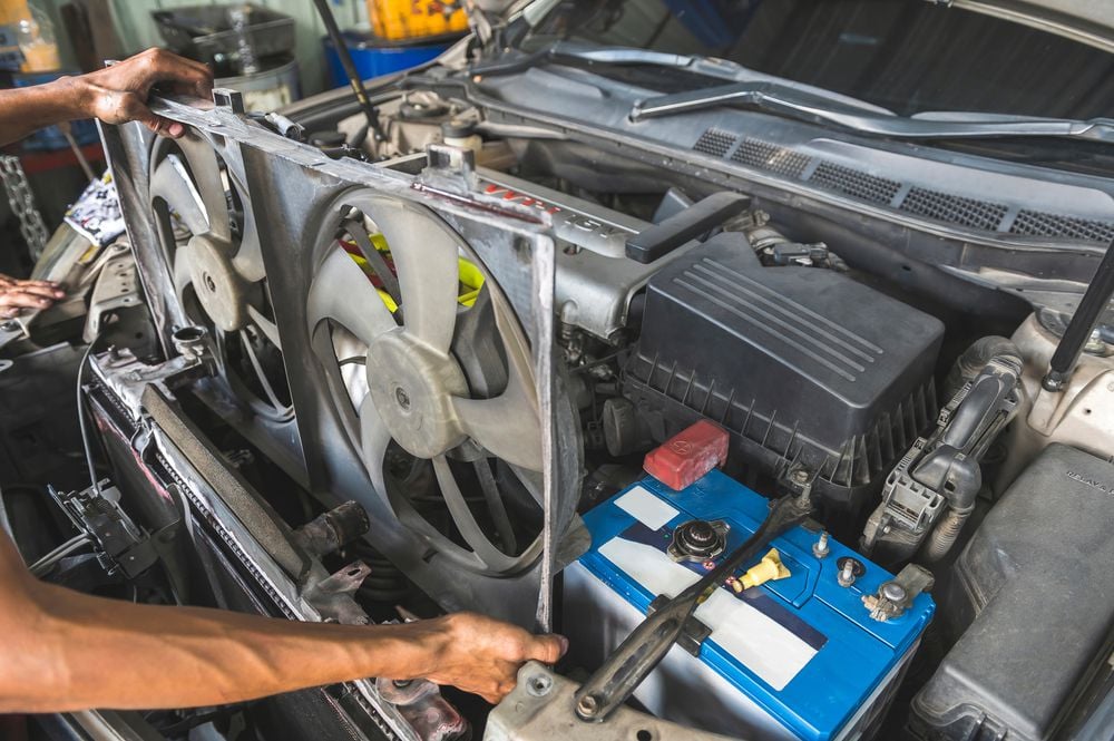 Car mechanic removing the radiator fan from the engine bay