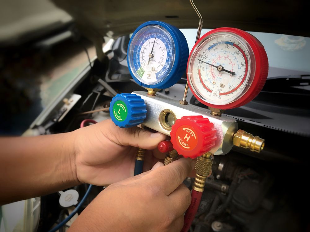 A mechanic servicing an AC compressor in a car.