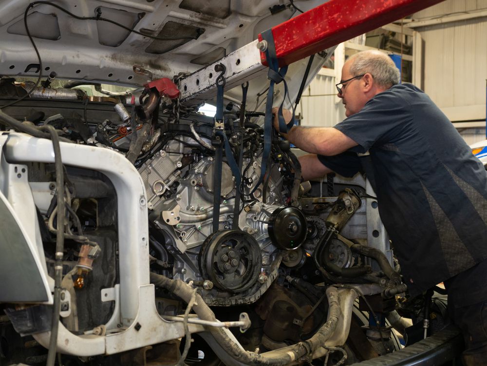 Mechanic swapping a new engine into a truck