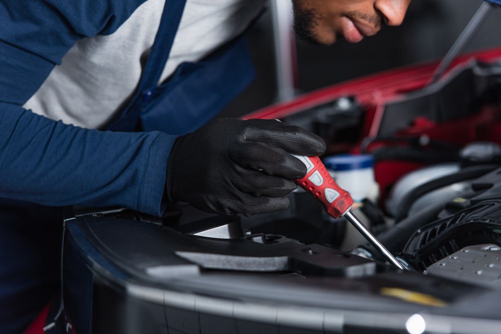 Mechanic testing an alternator with a screwdriver.