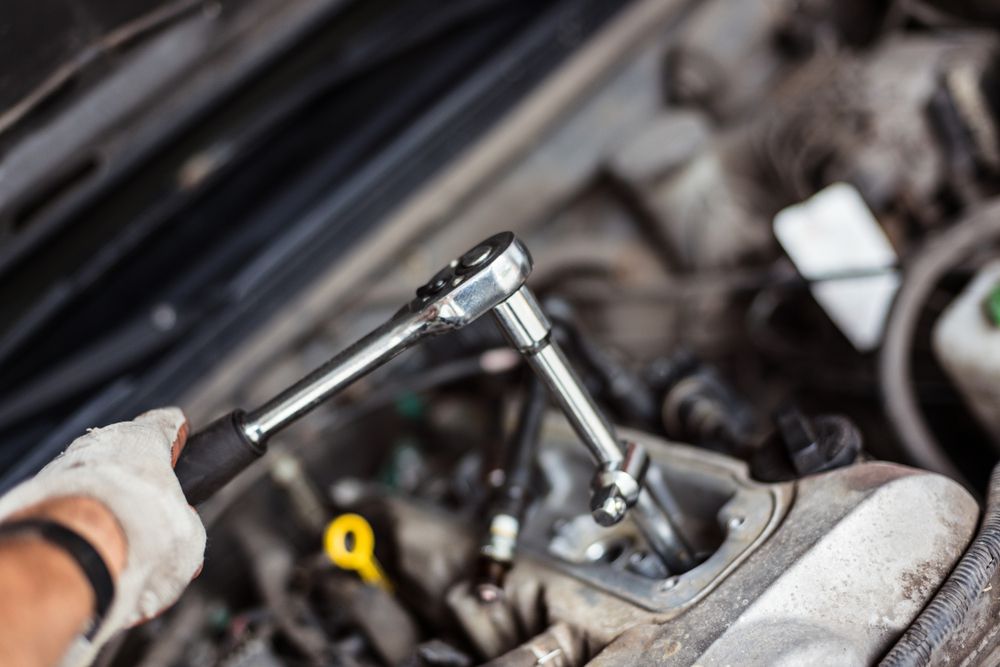 A mechanic tightening a loose spark plug.