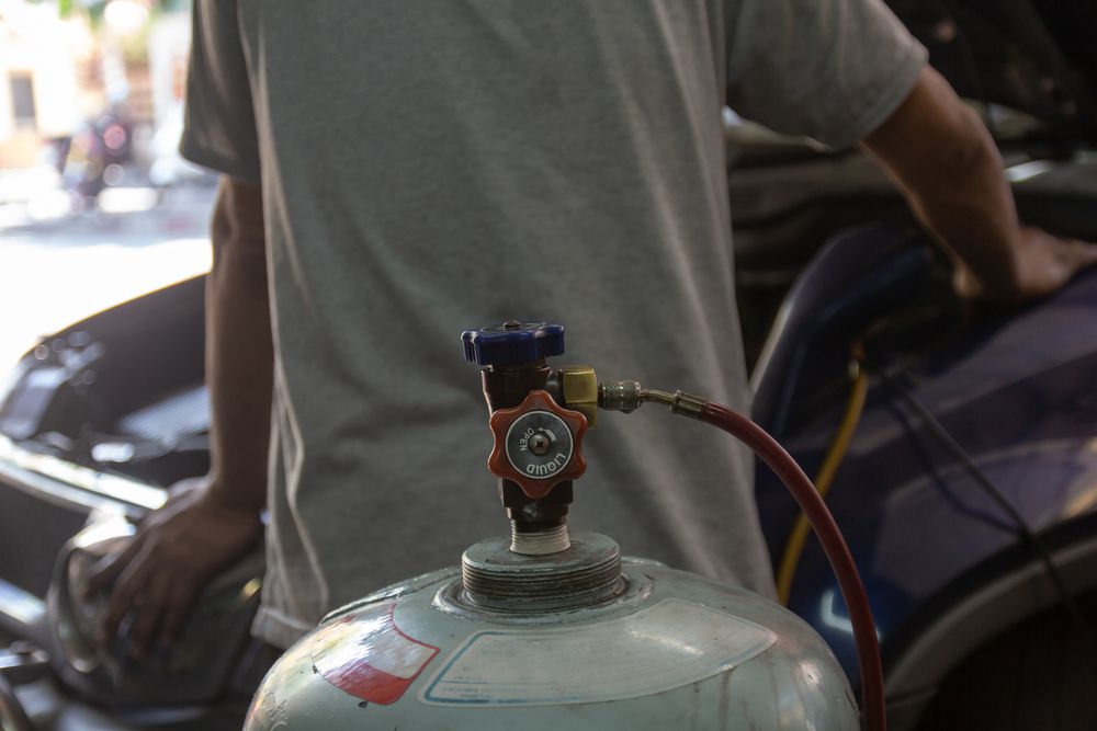 A mechanic recharging a car with freon.