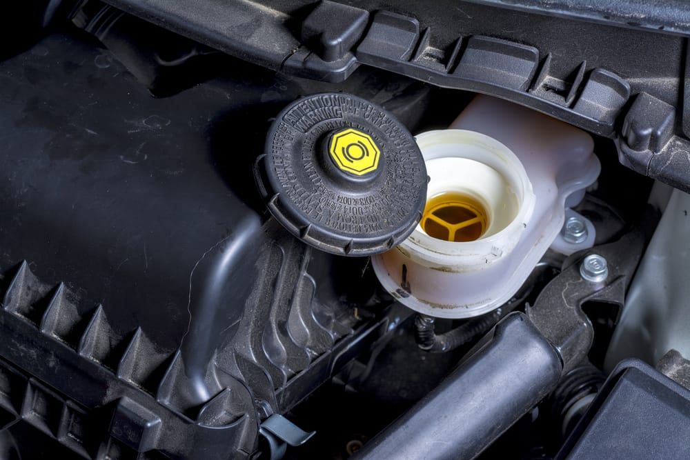 Removing the brake fluid cap before bleeding the brakes.