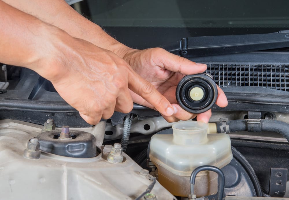 Removing the brake fluid cap and inspecting the fluid.