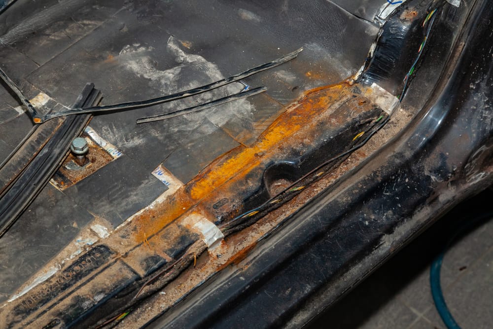 Rusty car floor caused by moisture.