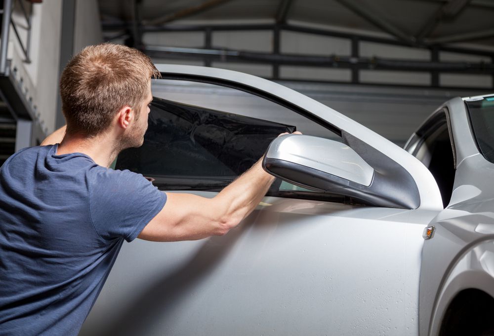 A technician applying window tint to a customer's car.