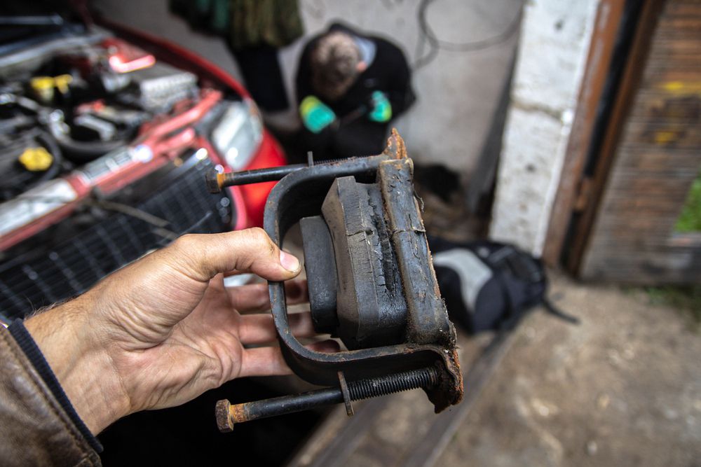 A torn engine mount in the mechanic's hand.