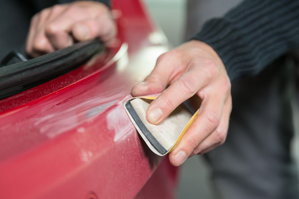 Using sandpaper to remove a scratch in a car