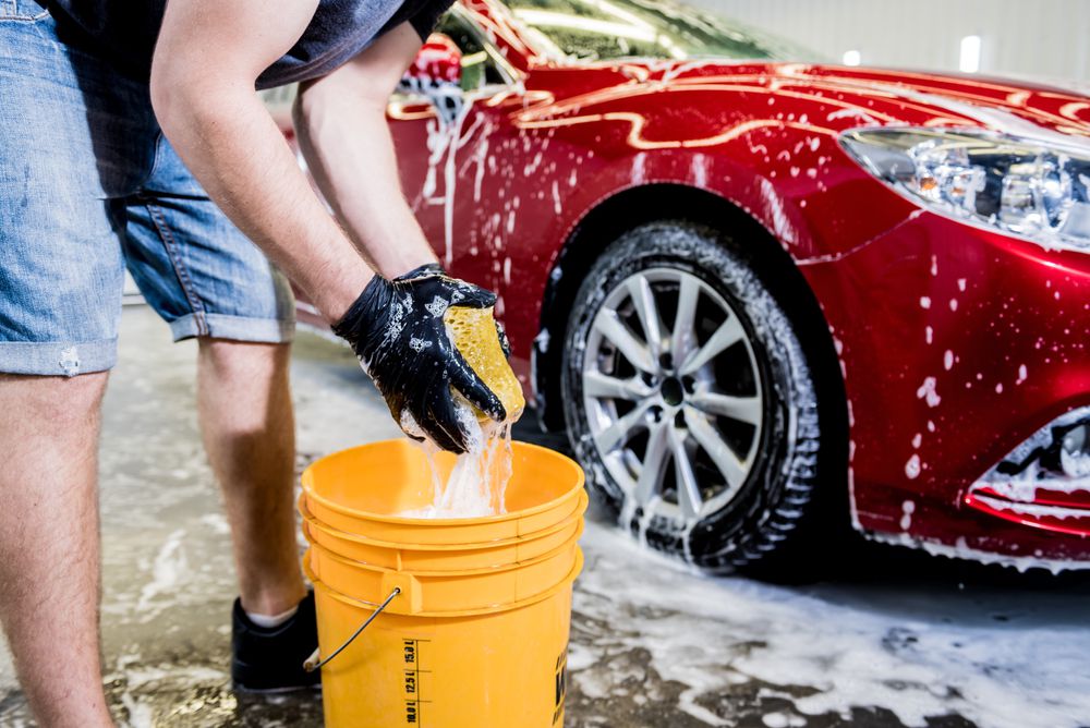 Washing a car with a bucket of water.