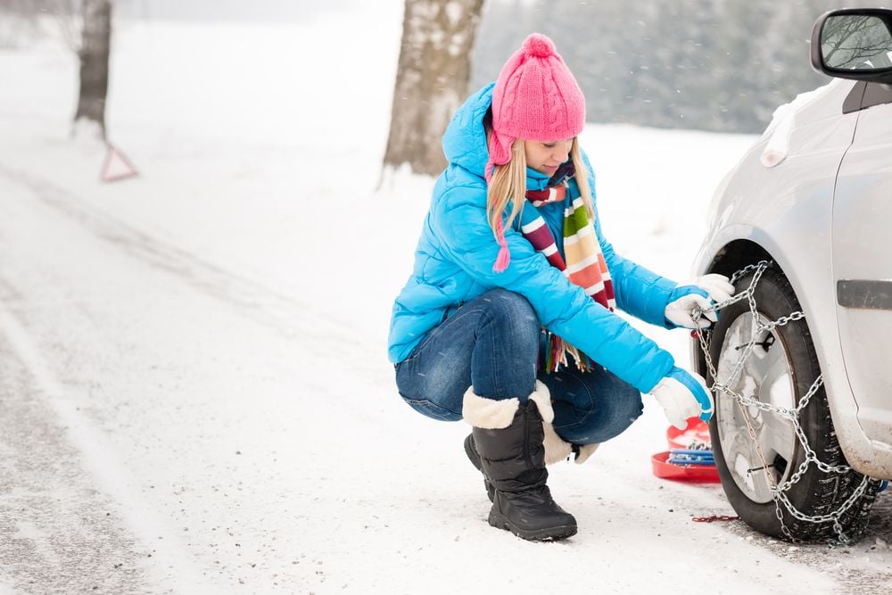 A woman installing snow chains.