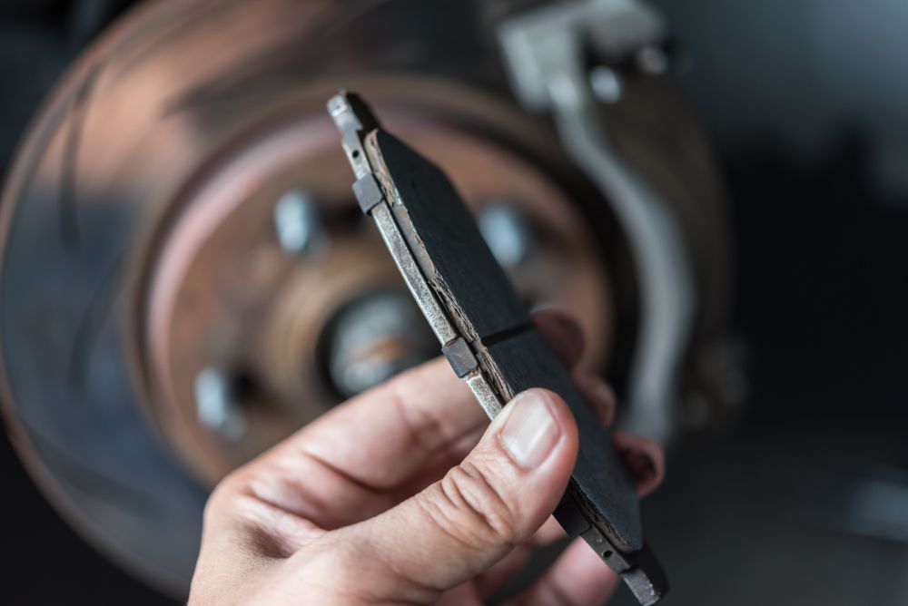 Mechanic showing worn brake pad