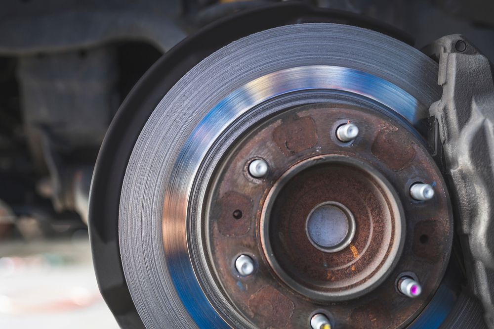 A mechanic inspecting a worn brake rotor.